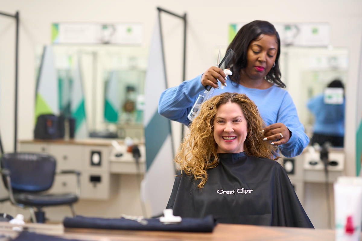 woman with curly hair getting a haircut in a Great Clips salon