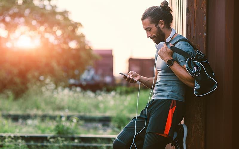 A man in workout clothes looking on his phone. 